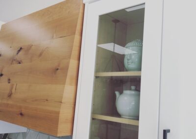 Custom, clear faced cabinets and a wooden hood fan