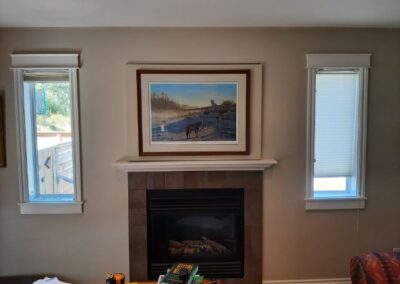 Photo of a fireplace hearth with a painting above, hiding a tv behind it.